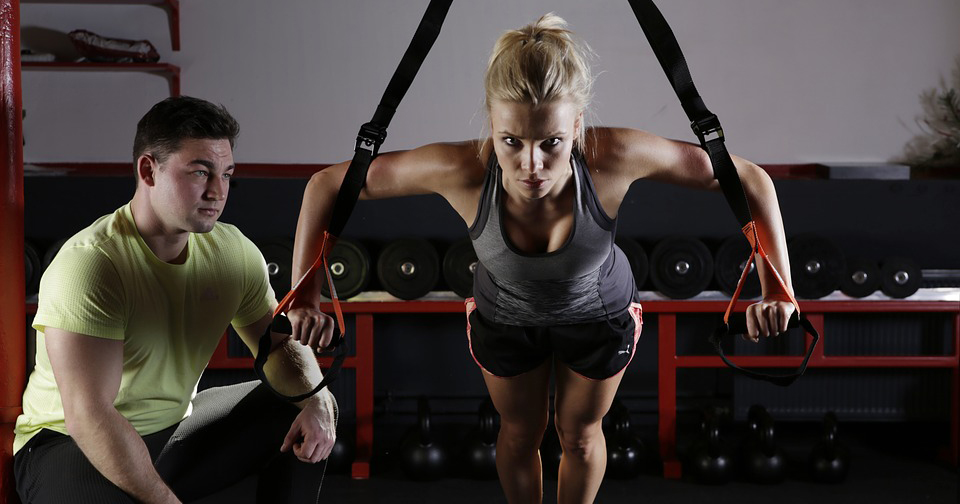 Woman working out with personal trainer spotting.