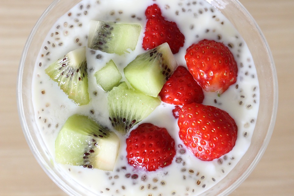 Chia seed pudding bowl with cut strawberries and kiwis on top.