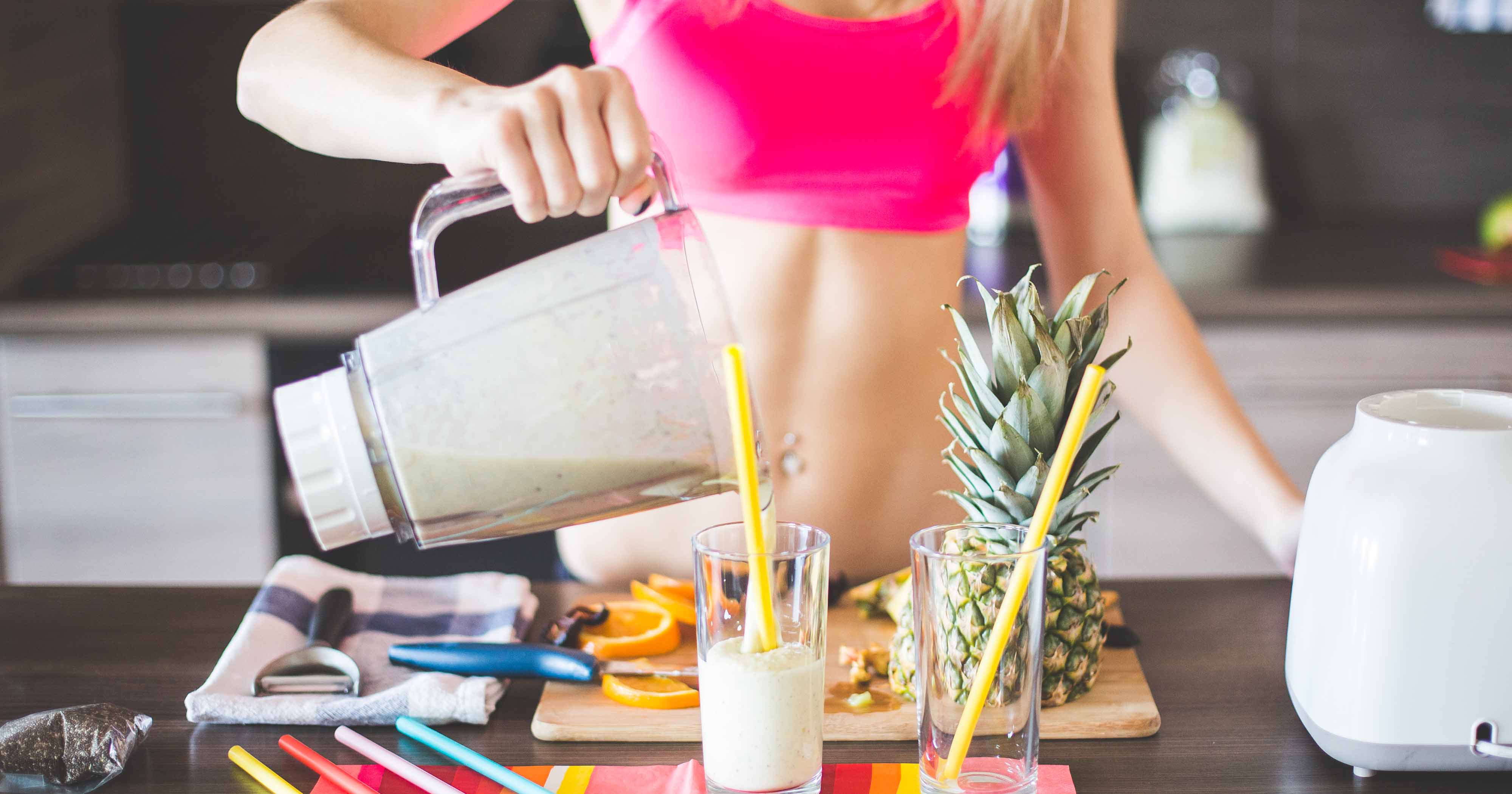 Woman pouring protein shake into glass on counter.