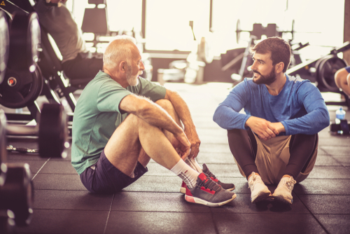 Older man resting in the gym with personal trainer.