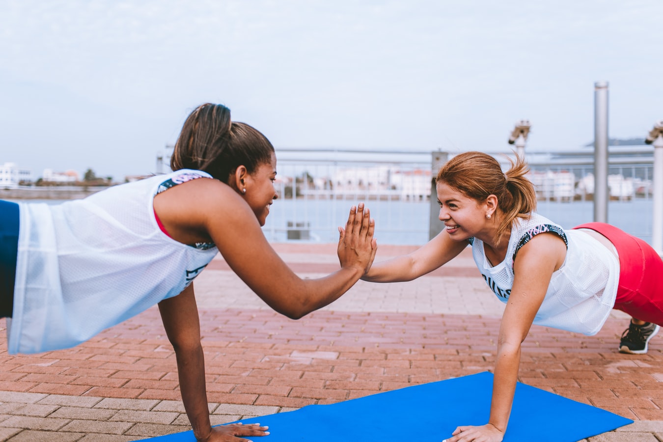 Two woman doing yoga on a pier.