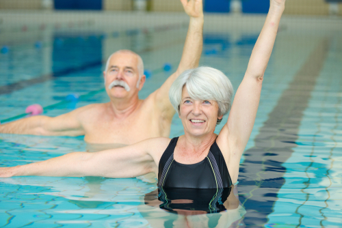 Older couple exercising in swimming pool.