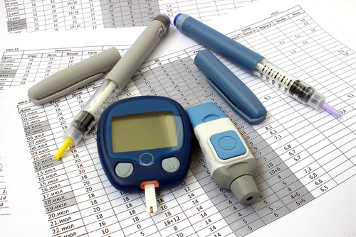 Blood sugar tester and diabetic medicine on top of paperwork.