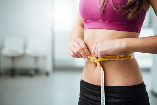 Woman taking waist measurements.