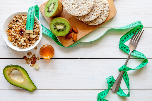 Table with various fruits and grains next to measuring tape.