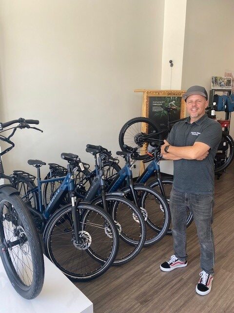 Man standing with bikes inside of Electric Bike Central.