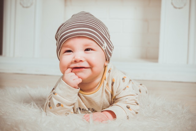 Baby on floor smiling at camera.