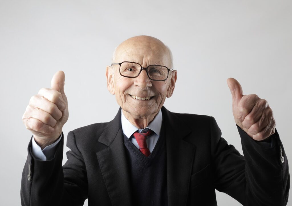 Older man holding two thumbs up.