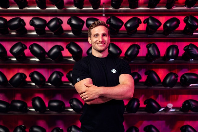 Man standing in front a wall lined with racks of dumbbells.