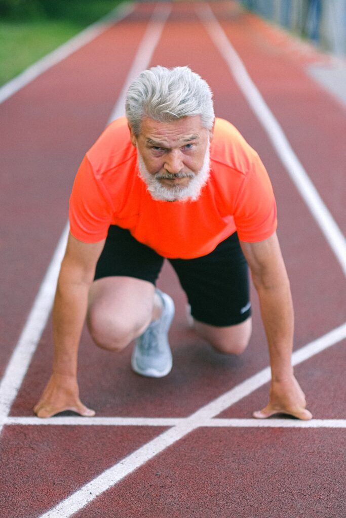 Older man getting ready to sprint on a track.