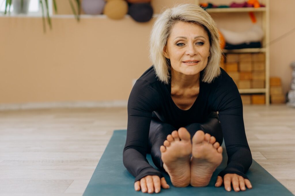 Older woman stretching in yoga pose past her toes.