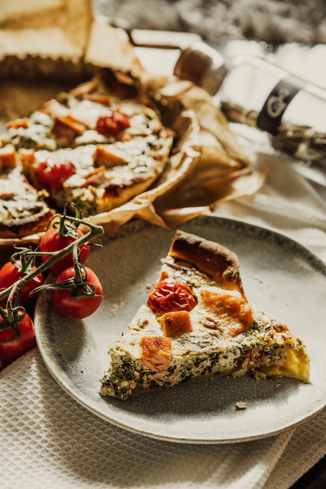 Pizza shown on table with one slice on a dinner plate.