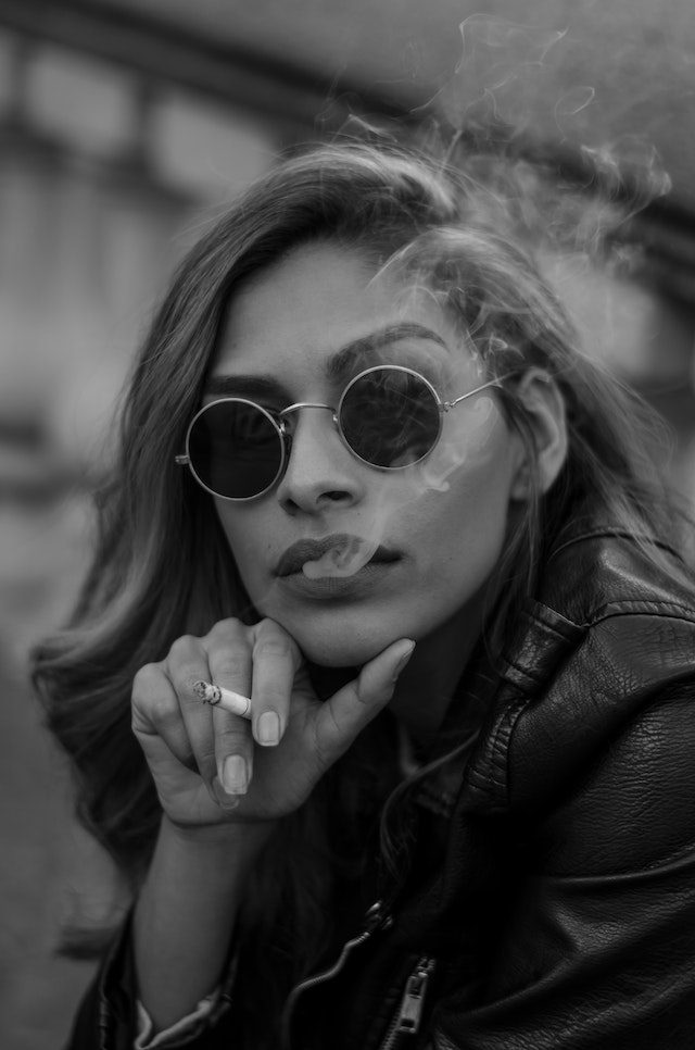Woman wearing sunglasses and smoking a cigarette.