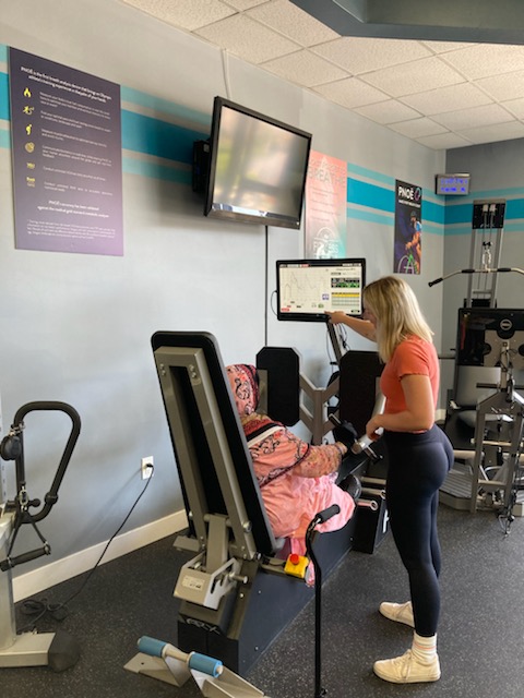 Woman working with personal trainer on ARX machine at Leo's Fitness Lab.