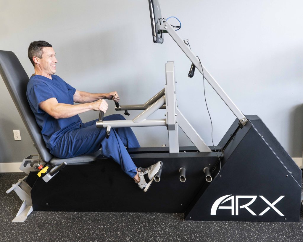 Man in scrubs working out on ARX machine at Leo's Fitness Lab for healthy weight lost.