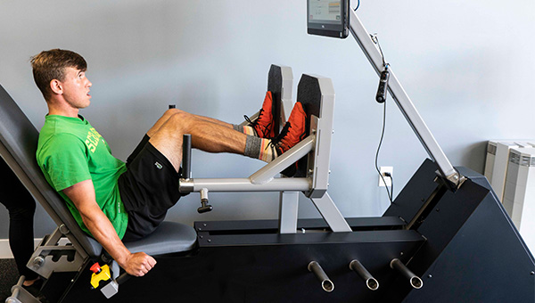 a young man using an ARX exercise equipment machine for a leg workout