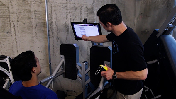 a image of a personal trainer instructing a customer on how to use an ARX workout machine