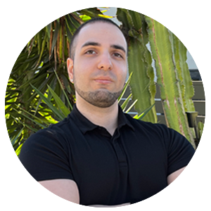 Man in black polo shirt standing with arms crossed in front of tropical bamboo plants