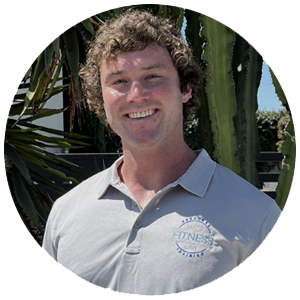 Young man with curly hair smiling in white Leo's Fitness Lab polo shirt with palm trees in background
