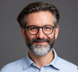 a headshot of an elderly man with glasses smiling at the camera