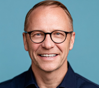 a headshot of a middle aged man with glasses smiling at the camera