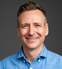 a headshot of a middle aged man smiling at the camera