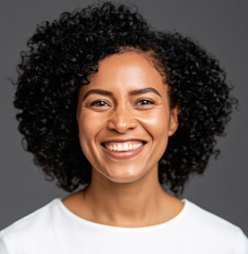 a headshot of a woman with curly black hair smiling at the camera