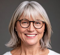 a headshot of an elderly woman with glasses smiling at the camera