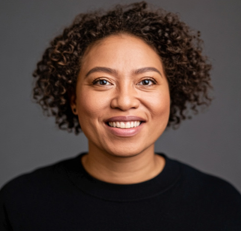 a headshot of a woman with curly black hair smiling at the camera